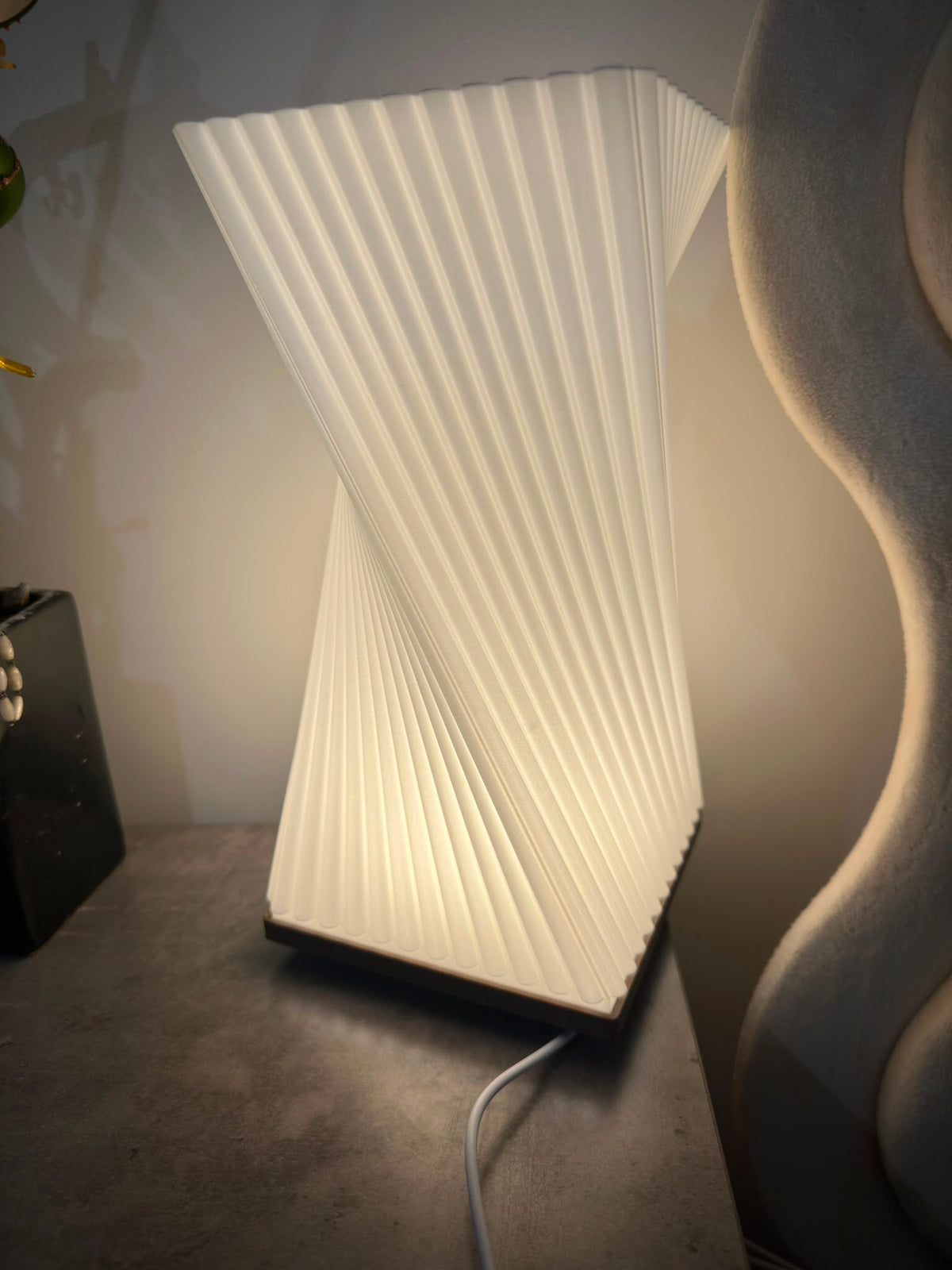 Twisted ribbed table lamp glowing with warm light, front view