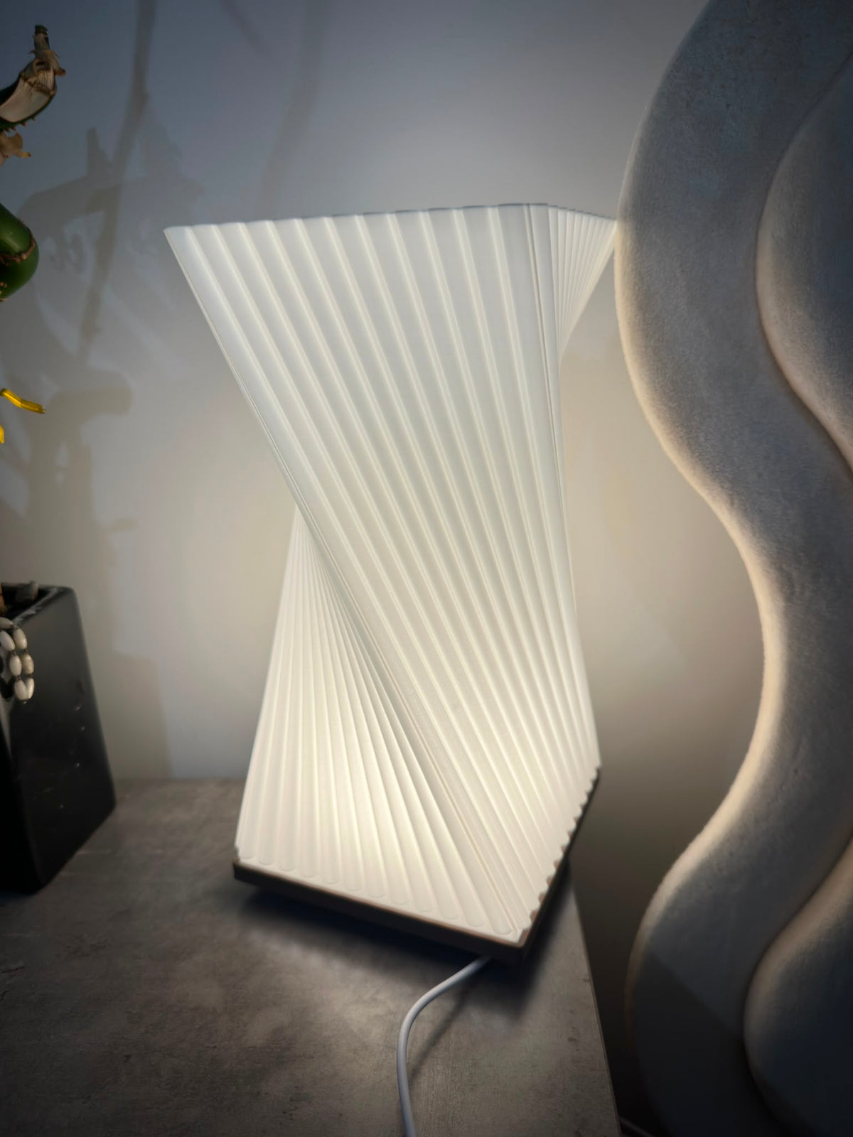 Twisted ribbed table lamp glowing with warm light, side view