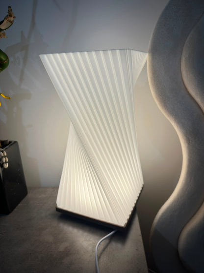 Twisted ribbed table lamp glowing with warm light, side view